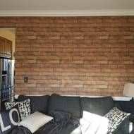 a living room filled with furniture and a brick wall behind the couch is a mirror