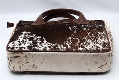 a brown and white animal print purse on a white surface with a handle in the shape of a handbag