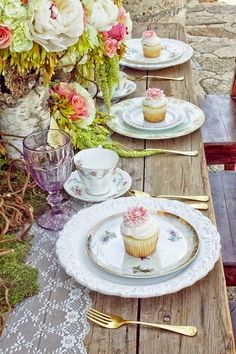 the table is set with cupcakes and flowers