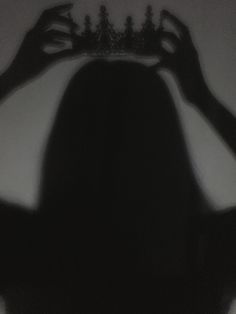 the shadow of a woman with a crown on her head and hands behind her head