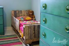 a small child's bedroom with green dressers and a wooden bed in the corner