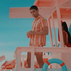 a man in an orange and white shirt standing on a boat with life preservers