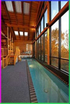 an indoor swimming pool in the middle of a room with lots of windows and stairs