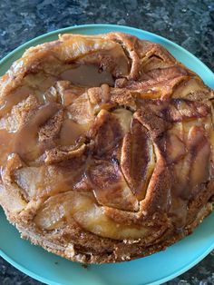 an apple pie on a blue plate with caramel sauce drizzled over it