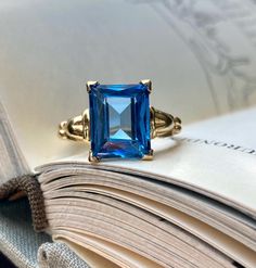 Beautiful rich blue gemstone vintage ring. The color of the blue is absolutely dazzling! The ring dates to the 1940s - 1960s approximately.  Solid 10K yellow gold. Emerald cut gemstone tests as topaz on my at-home SmartPro Gem Tester but looks more like it could be blue spinel, especially judging by the older setting and the high hardness rating. It is a gemstone, not glass, but I am not a Gemologist.  Signed and tested real 10K gold. Size 5 US; resizable by your local jeweler.  Measures 10 mm t 10k Gold Ring, Blue Spinel, Spinel Gemstone, Blue Gemstones, Vintage Ring, 10k Gold, Emerald Cut, Rings Statement, Vintage Rings