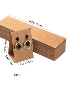 two pairs of earrings are in a cardboard box with measurements for each pair and price