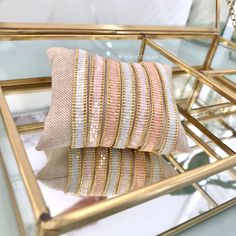 two decorative pillows sitting on top of a glass table next to a gold framed mirror