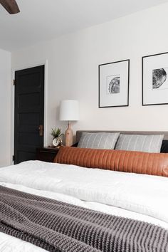 a large bed sitting in a bedroom next to two pictures on the wall above it