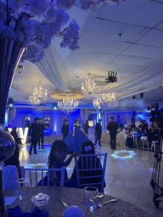 a group of people sitting at tables in a room with chandeliers hanging from the ceiling