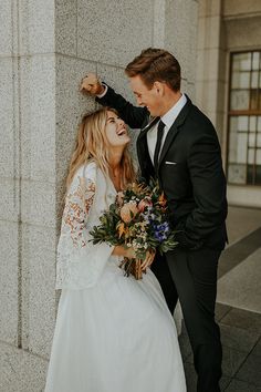 a man in a suit and tie standing next to a woman wearing a wedding dress