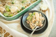 a black plate topped with food next to a casserole filled with broccoli