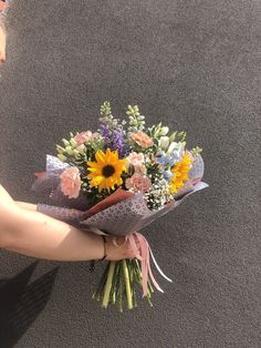 a person holding a bouquet of flowers in their hand on the ground with grey carpet