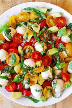 a white plate filled with lots of different types of vegetables on top of a wooden table