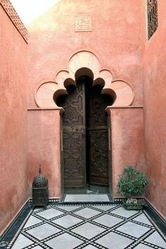 an entrance to a pink building with intricately designed doors and windows, in the middle of a tiled floor