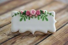 a decorated cookie with pink roses and green leaves