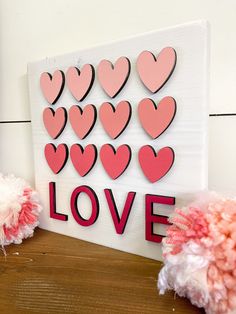 valentine's day decorations made out of paper hearts on a wooden table with pink pom poms