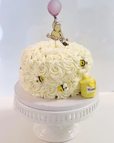 a winnie the pooh cake with white frosting and honeybees on top