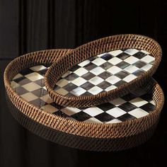 two wicker trays sitting on top of each other in front of a black wall