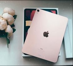 an apple ipad in its box next to some flowers