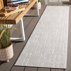 a large white rug on top of a wooden bench next to a potted plant