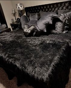 a bed with black fur and pillows on it