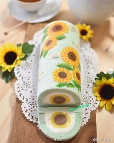 a cake decorated with sunflowers on a doily next to a cup of coffee