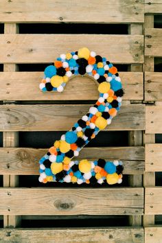 the number two made out of pom - poms is displayed on wooden pallets