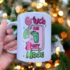 a person holding a coffee mug in front of a christmas tree with the words grin on it