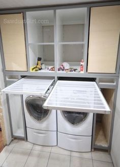 a washer and dryer in a small room with cabinets on the wall behind them