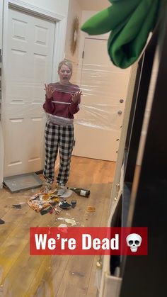 a woman standing in the middle of a kitchen with trash all over her floor and walls