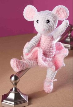 a crocheted mouse in a pink dress sitting on top of a metal ball