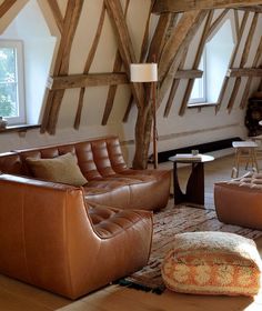 a living room with leather furniture and exposed wood beams on the ceiling, along with an ottoman