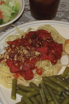 a plate with pasta, green beans and bread next to a bowl of salad on a table