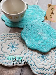 blue and white placemats with snowflakes on them next to a coffee cup