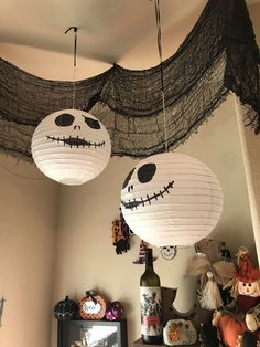 two paper lanterns hanging from the ceiling in a room decorated for halloween with skeletons and jack - o - lantern faces