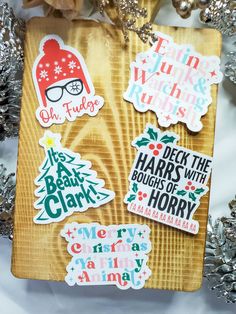 christmas stickers on a wooden board next to tinsel