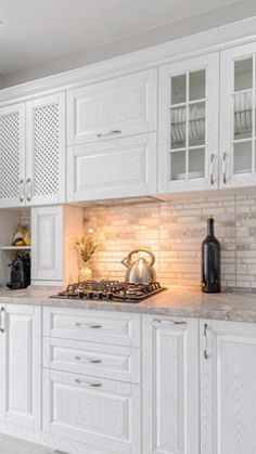 a kitchen with white cabinets and marble counter tops