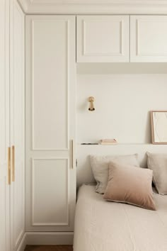 a bedroom with white walls and wooden flooring is pictured in this image, there are pillows on the bed