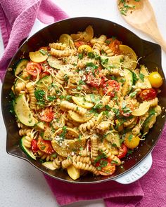 a pan filled with pasta and vegetables on top of a pink towel