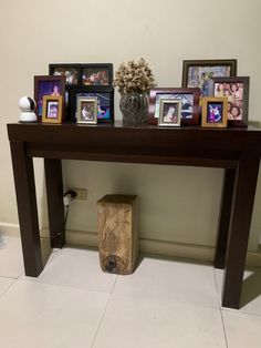 a wooden table with pictures on it and a vase filled with flowers next to it