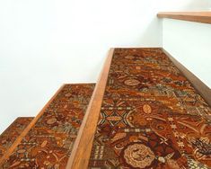 an area rug on the bottom of a stair case with wooden handrails and white walls