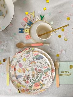 a birthday party table setting with confetti, plates and utensils on it