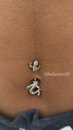 a woman's stomach with two silver charms attached to it