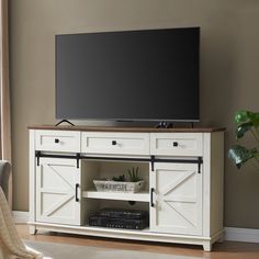 a flat screen tv sitting on top of a white entertainment center next to a window