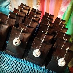 small brown bags with disco balls hanging from them on a blue tablecloth covered table