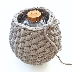 a small crocheted basket with a candle in the middle and a cord attached to it