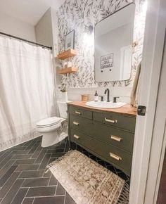 a bathroom with black and white tile flooring and wallpaper, along with a green vanity