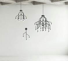 three chandeliers hanging from the ceiling in an empty room with white walls and concrete beams