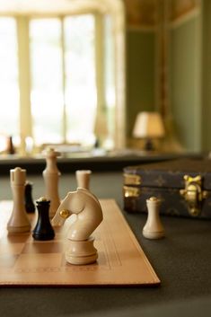 a chess board with pieces on it and a suit case in the back ground next to them