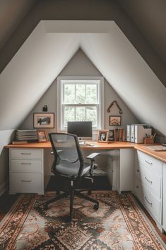 an attic office with a desk and chair in the corner, on top of a rug